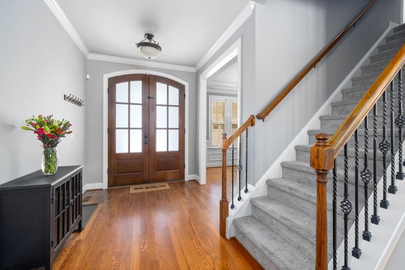 Solid wood entrance door in a home foyer beside a staircase