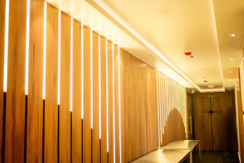 Corridor with wood-panelled false ceiling and recessed ambient lighting
