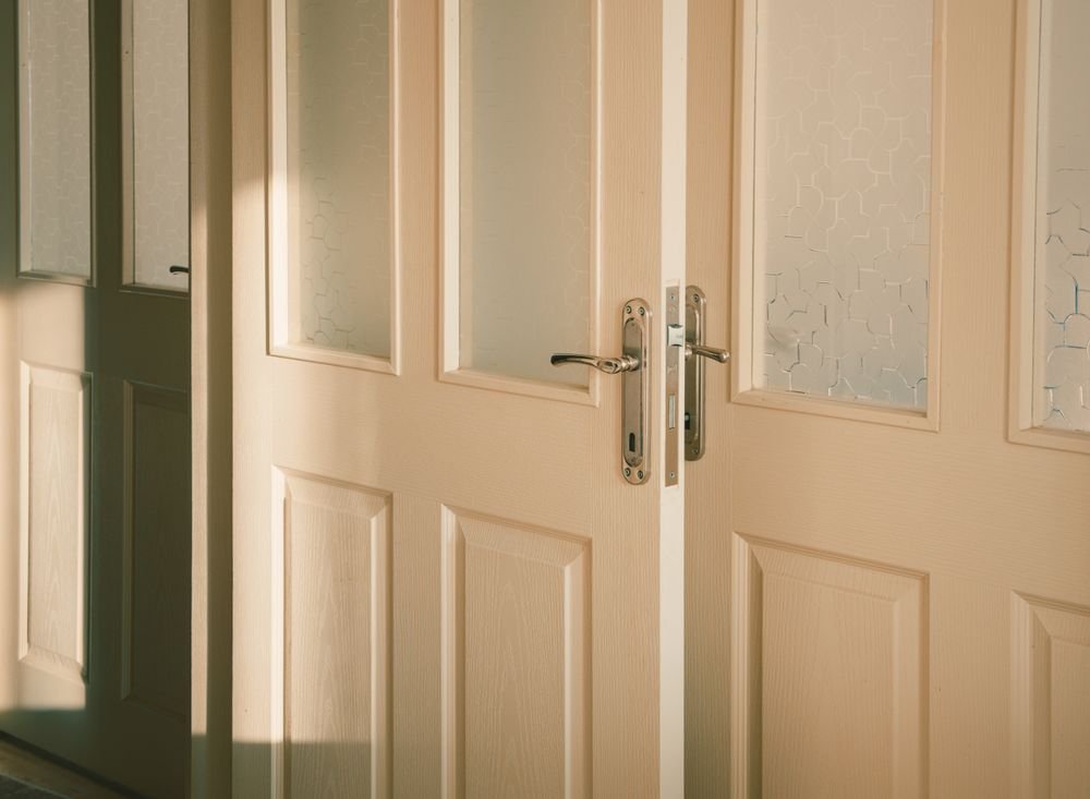 Wooden entrance doors with frosted glass panels at a private villa