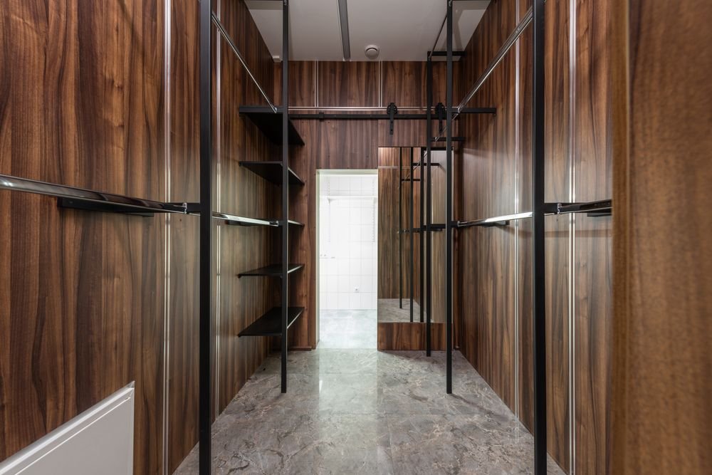 Walk-in wardrobe with wooden paneling and open storage in a Ludhiana apartment