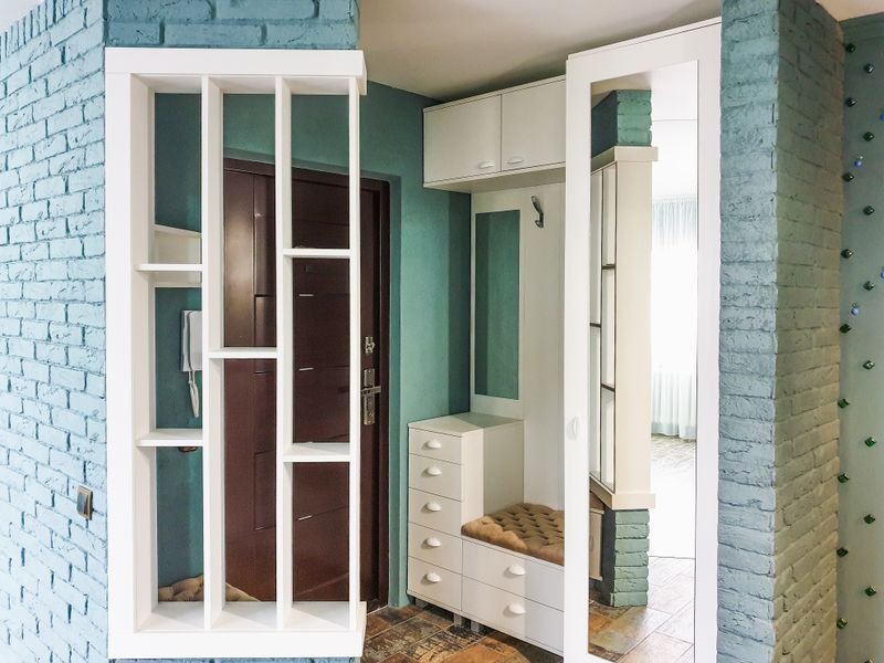 Entryway shoe cabinet with open shelving against a brick wall
