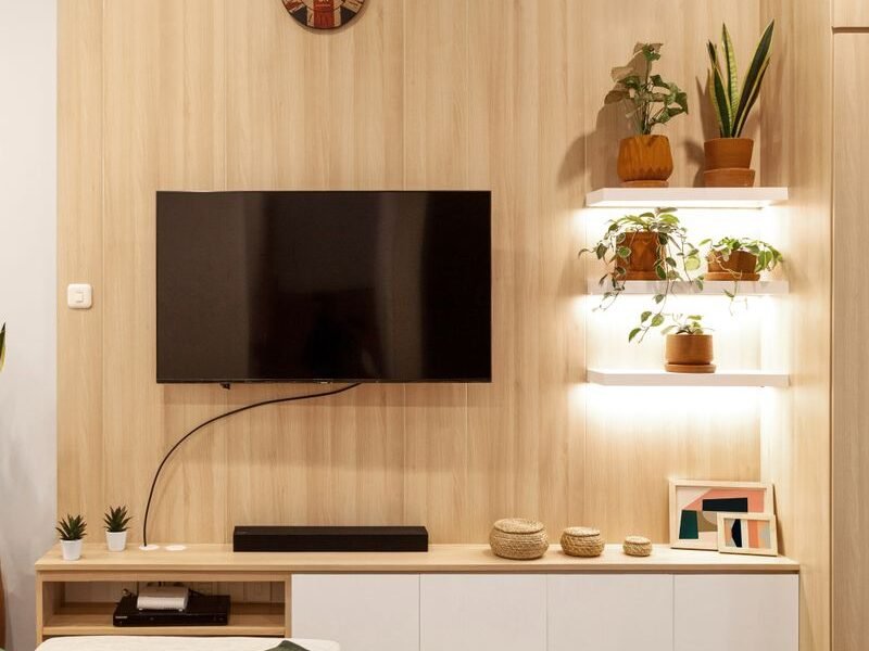 Wall-mounted TV unit with open wooden shelving in a living room